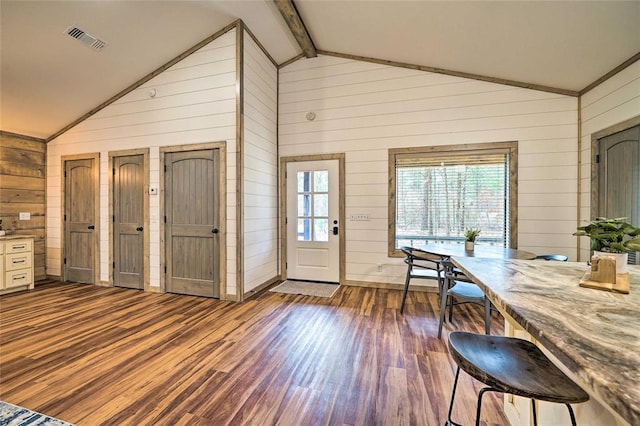 entrance foyer with beam ceiling, dark wood-style flooring, visible vents, and wooden walls