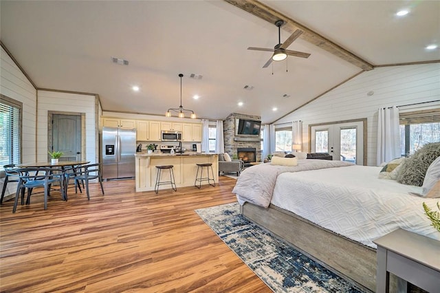 bedroom with vaulted ceiling with beams, wood walls, visible vents, stainless steel fridge with ice dispenser, and light wood finished floors