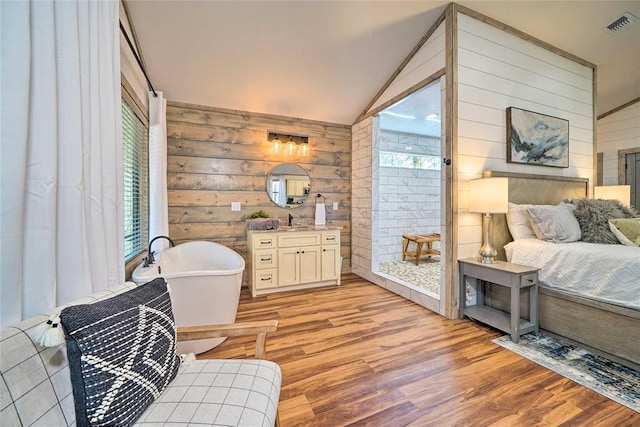 sitting room featuring lofted ceiling, light wood-style floors, visible vents, and wood walls