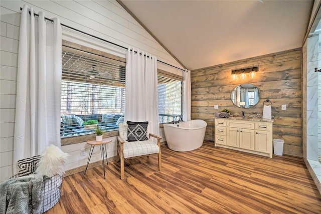 sitting room featuring vaulted ceiling, wooden walls, and light wood finished floors