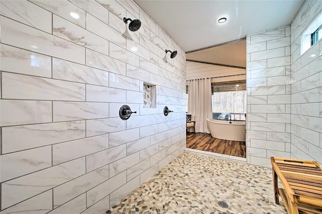 bathroom featuring tiled shower, a freestanding bath, and tile walls