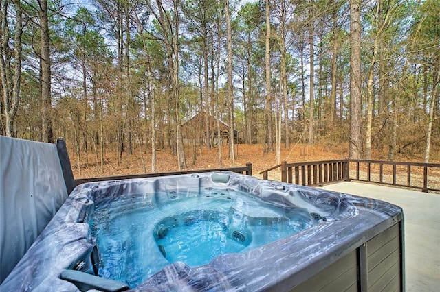 view of swimming pool featuring a view of trees and a hot tub