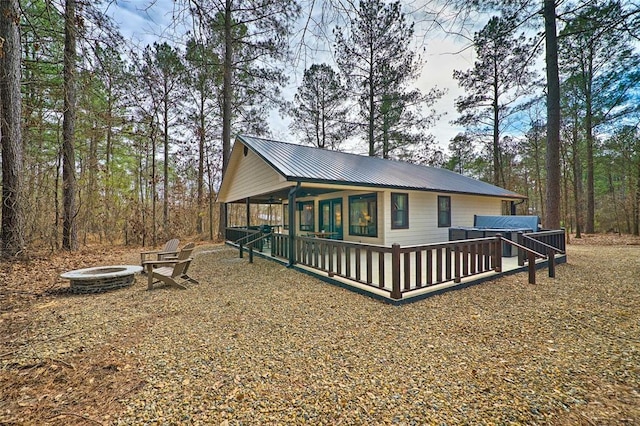 back of house with metal roof and an outdoor fire pit