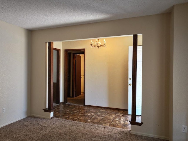 unfurnished room featuring a textured ceiling, dark carpet, and a notable chandelier