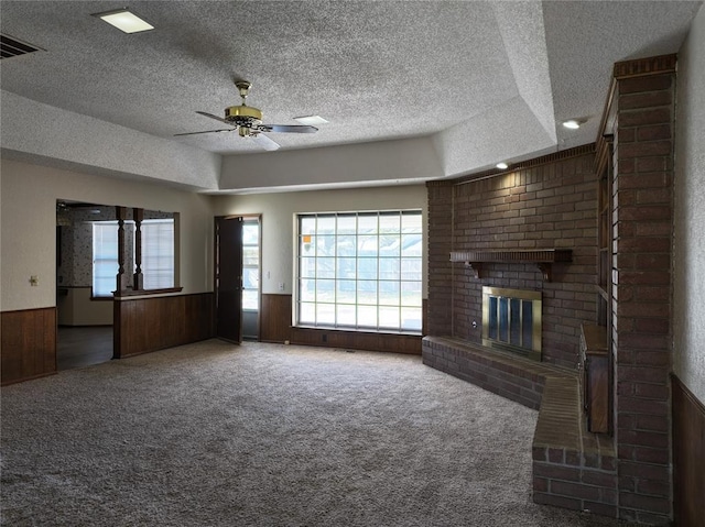 unfurnished living room with a wainscoted wall, a fireplace, wooden walls, and a textured ceiling