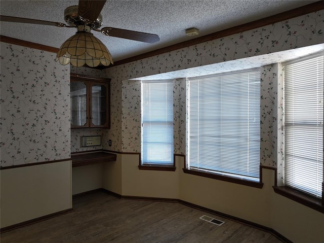 unfurnished room with dark wood-type flooring, visible vents, a textured ceiling, and wallpapered walls