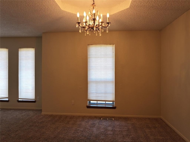 carpeted empty room featuring a notable chandelier, a textured ceiling, visible vents, and baseboards