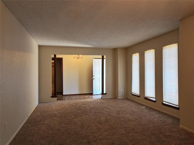 unfurnished room with light colored carpet, a textured ceiling, and baseboards