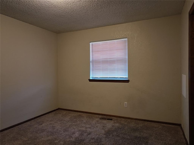 carpeted spare room featuring visible vents, a textured ceiling, and baseboards