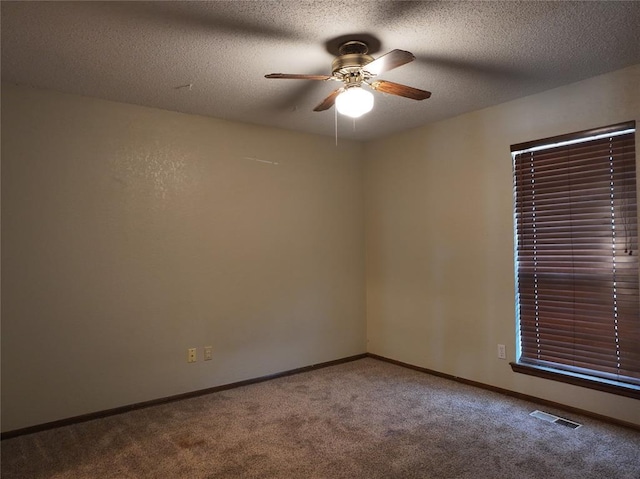 carpeted spare room featuring a ceiling fan, baseboards, visible vents, and a textured ceiling