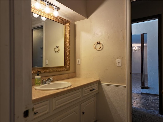 bathroom featuring a textured wall, stone finish floor, and vanity