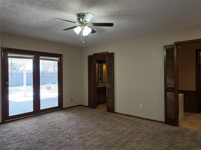 carpeted spare room with a textured ceiling, visible vents, a ceiling fan, and baseboards