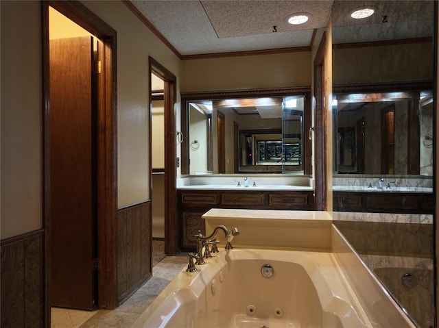 bathroom featuring a wainscoted wall, crown molding, a sink, a textured ceiling, and a tub with jets