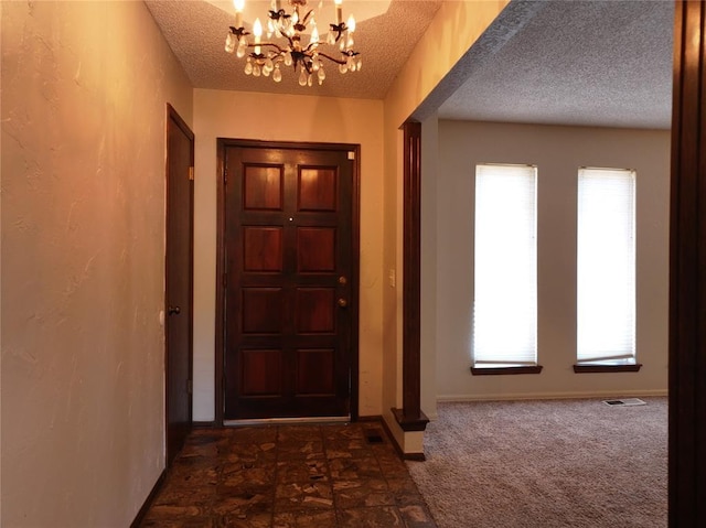 interior space with a notable chandelier, dark colored carpet, visible vents, a textured ceiling, and baseboards