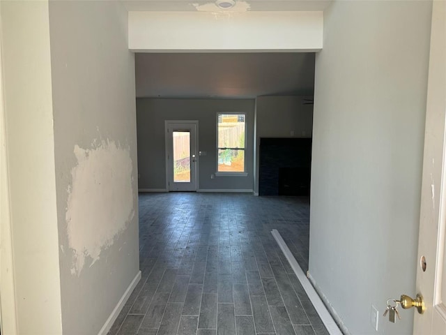 hallway featuring dark wood-type flooring and baseboards