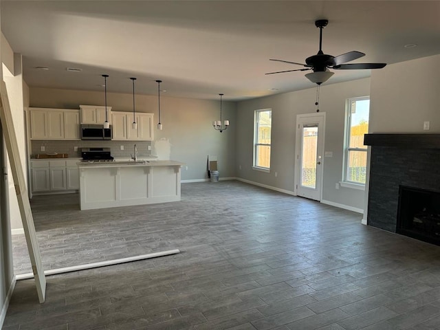 kitchen featuring stainless steel appliances, light countertops, open floor plan, white cabinetry, and a sink