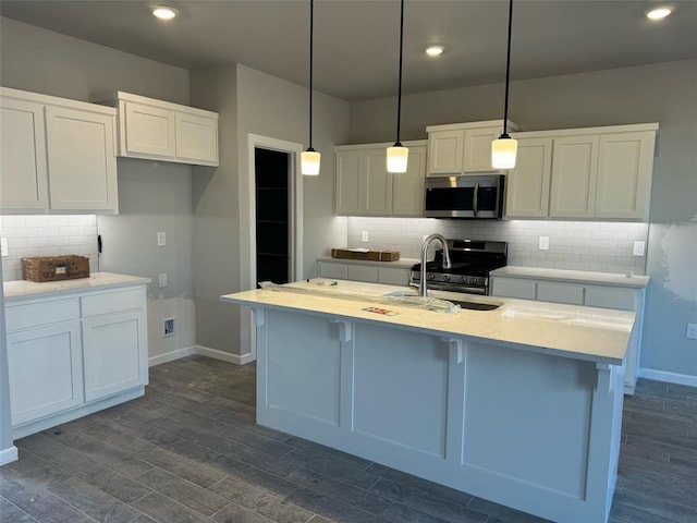 kitchen featuring an island with sink, white cabinetry, appliances with stainless steel finishes, and pendant lighting