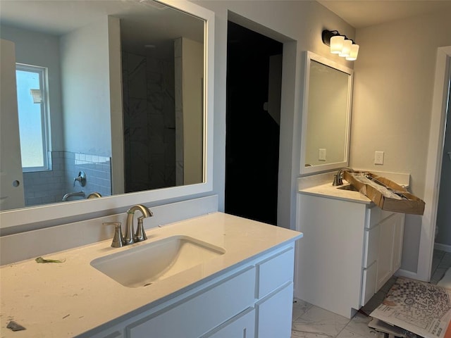 full bathroom featuring marble finish floor, a shower, and vanity