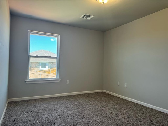 unfurnished room with a wealth of natural light, carpet, visible vents, and baseboards