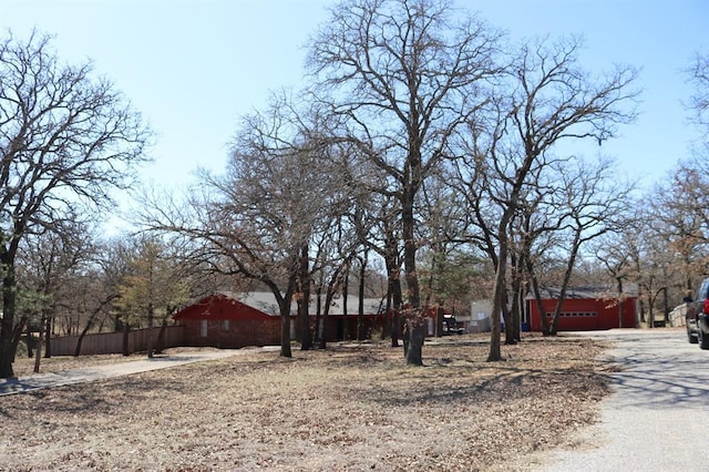 view of yard featuring driveway, an attached garage, and fence