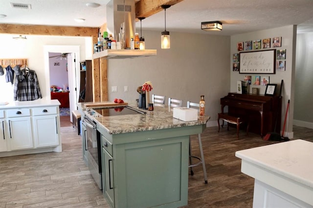 kitchen featuring visible vents, green cabinets, extractor fan, a kitchen breakfast bar, and electric range