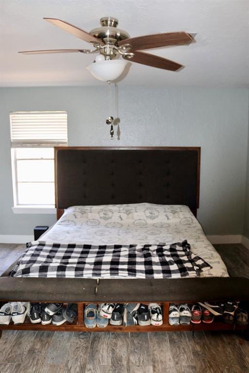 bedroom with ceiling fan, baseboards, and wood finished floors