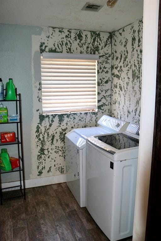 washroom featuring dark wood-style floors, visible vents, wallpapered walls, laundry area, and separate washer and dryer