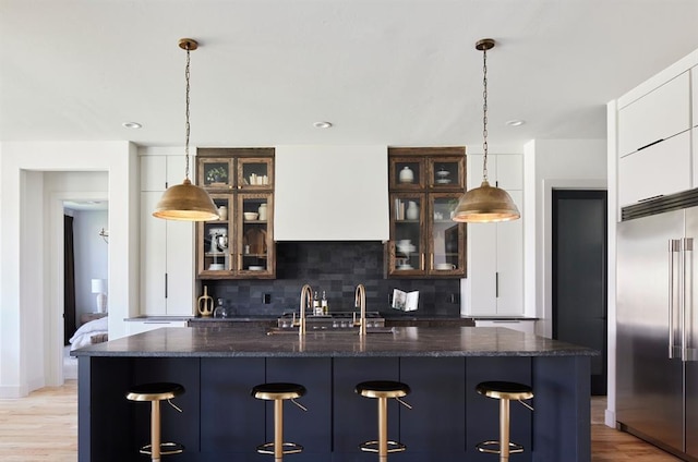 kitchen featuring glass insert cabinets, decorative light fixtures, built in refrigerator, and white cabinetry