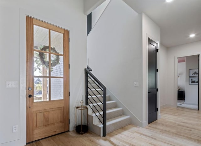 foyer entrance featuring light wood-style floors, plenty of natural light, stairway, and baseboards