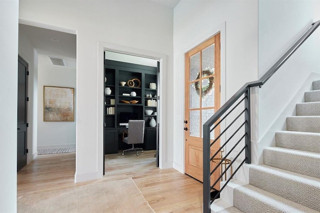 foyer entrance with stairway, light wood-type flooring, visible vents, and baseboards