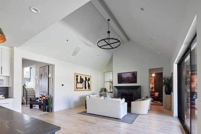 living room with light wood finished floors, a fireplace, beam ceiling, and a notable chandelier