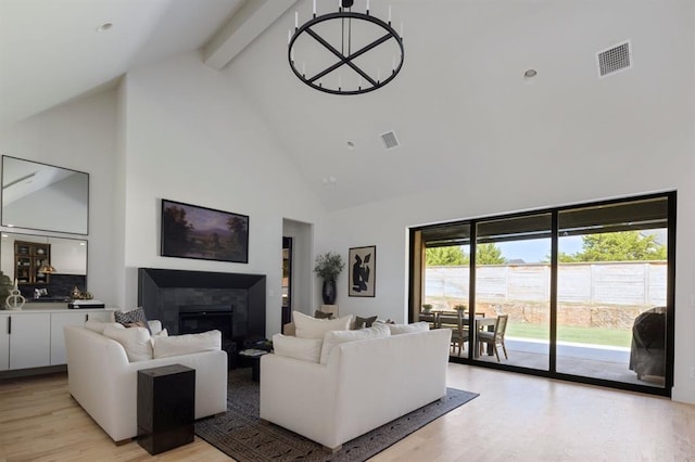 living area featuring light wood finished floors, beam ceiling, visible vents, and a tiled fireplace