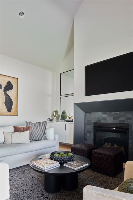 living area with high vaulted ceiling and a tile fireplace