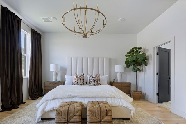 bedroom with light wood-style floors and an inviting chandelier