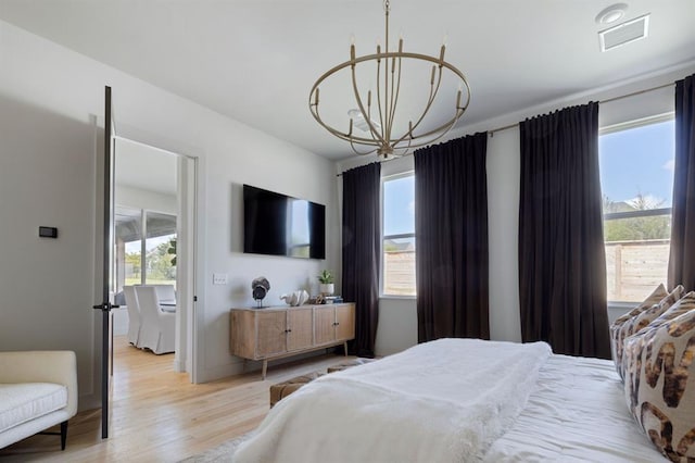 bedroom featuring multiple windows, light wood-type flooring, visible vents, and an inviting chandelier