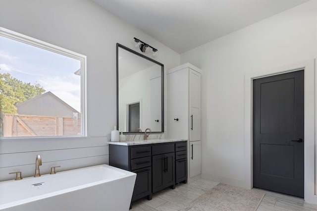 full bathroom with marble finish floor, a freestanding bath, and vanity