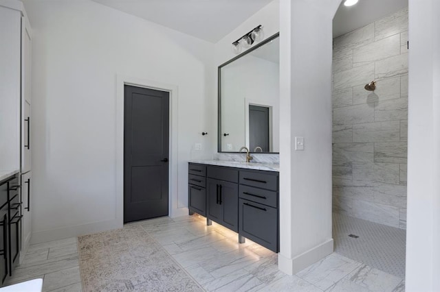 full bath with marble finish floor, vanity, baseboards, and a walk in shower