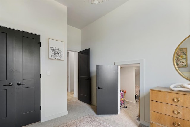 bedroom featuring baseboards, light colored carpet, and a high ceiling