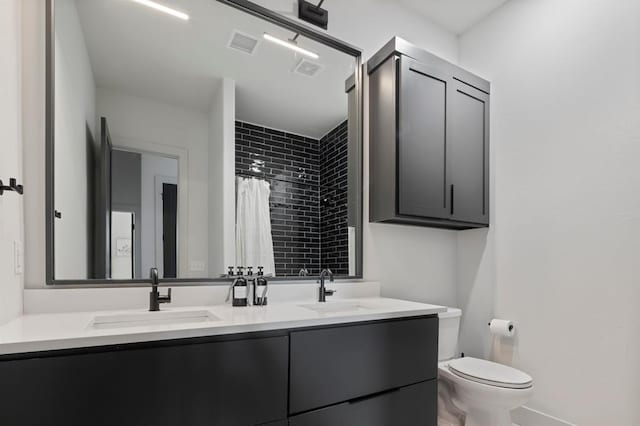 bathroom with toilet, double vanity, a sink, and visible vents