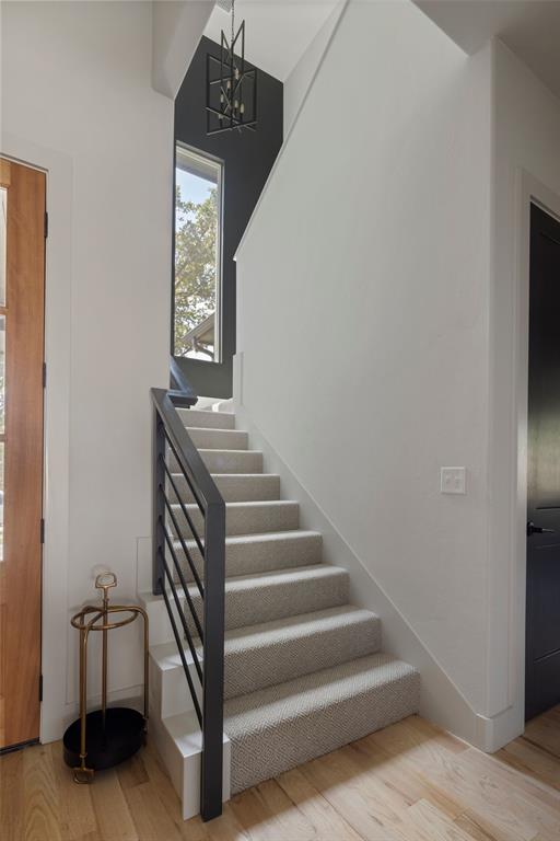 stairway featuring a notable chandelier and wood finished floors