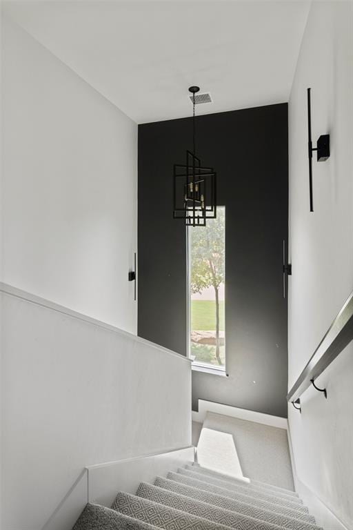 stairs featuring carpet floors, visible vents, and an inviting chandelier