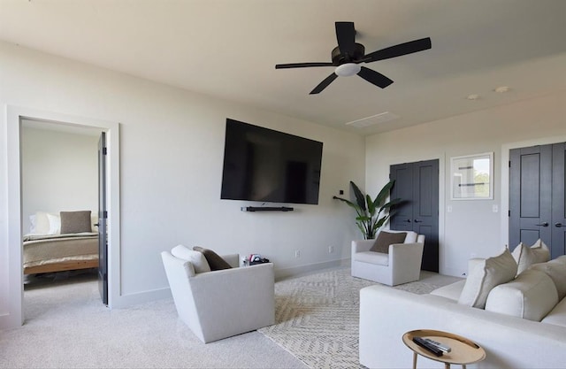 living area with baseboards, a ceiling fan, and light colored carpet