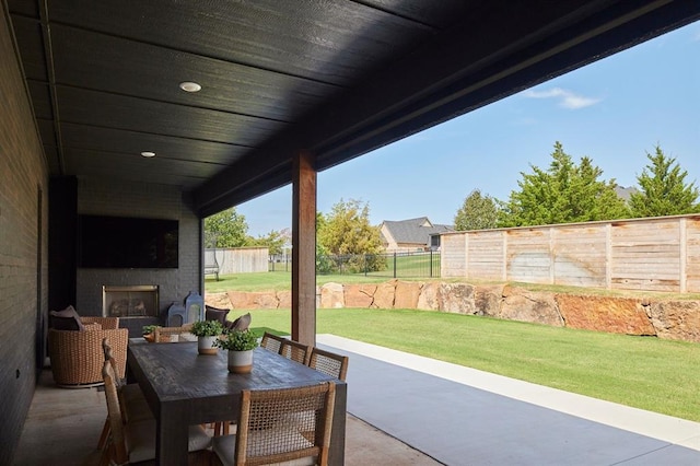 view of patio / terrace featuring a large fireplace, outdoor dining space, and a fenced backyard