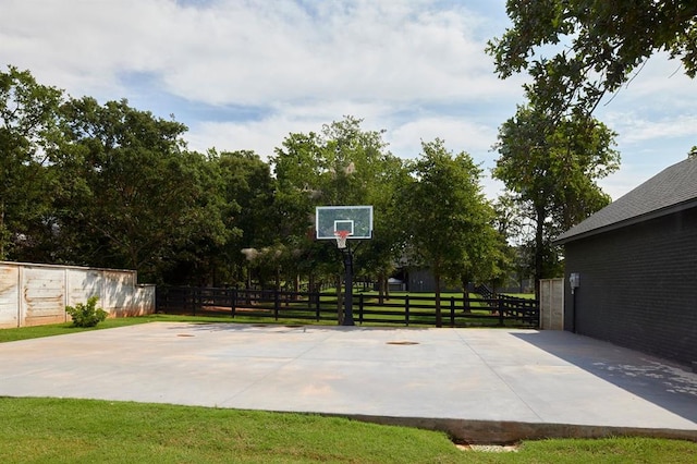 view of basketball court with community basketball court, fence, and a lawn