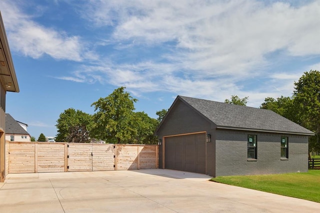 view of side of property featuring roof with shingles, a detached garage, fence, and brick siding