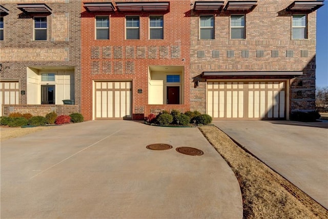 view of front of home featuring a garage, concrete driveway, and brick siding