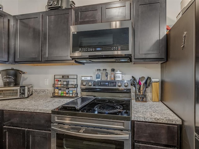 kitchen featuring dark brown cabinetry, a toaster, and appliances with stainless steel finishes