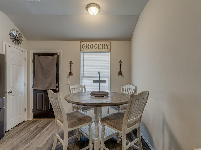 dining space with lofted ceiling and wood finished floors