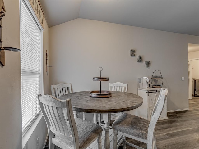 dining area with light wood-style floors, vaulted ceiling, and baseboards