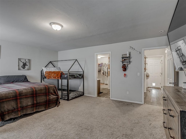 bedroom featuring light carpet, connected bathroom, and baseboards